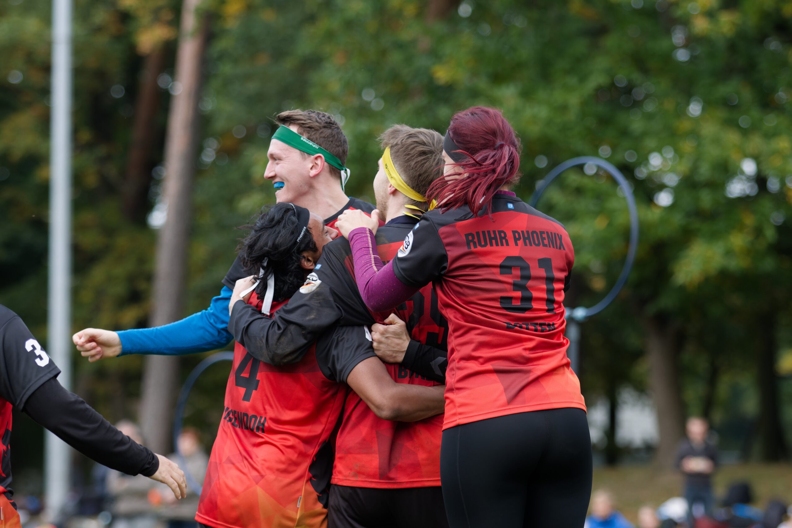 Unser Verein Quadballspieler:innen in roten Trikots umarmen sich freudig