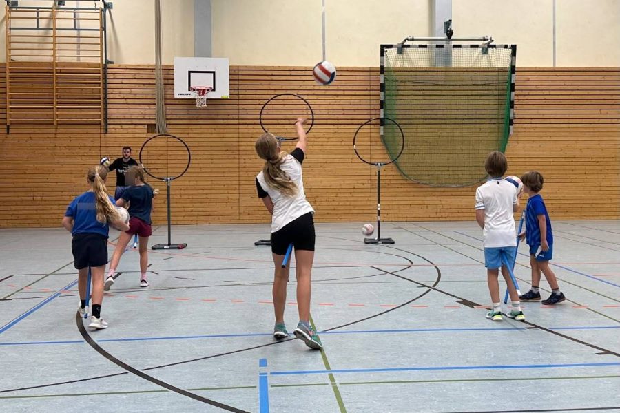 Kidditch Kinder werfen Bälle auf Ringe in einer Turnhalle