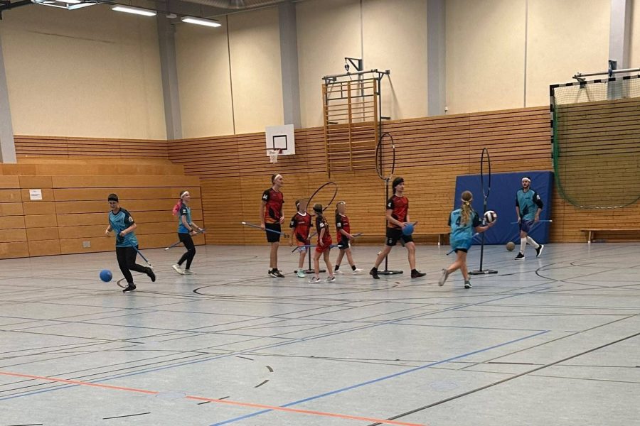 Kidditch Eine Gruppe von Kindern und Erwachsenen spielen zusammen Kidditch