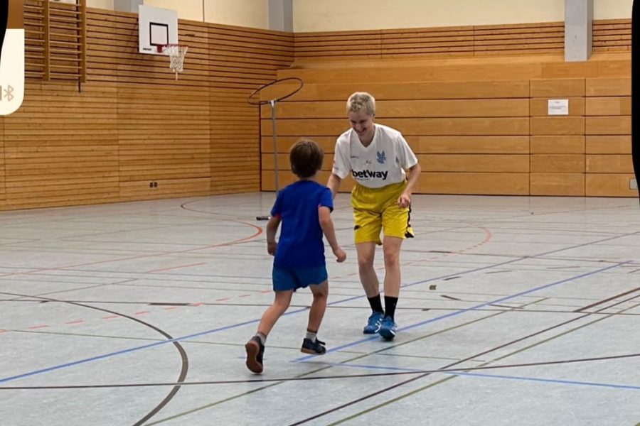 Kidditch Ein Junge versucht einer Frau die Socke mit Tennisball an ihrer Hose abzunehmen