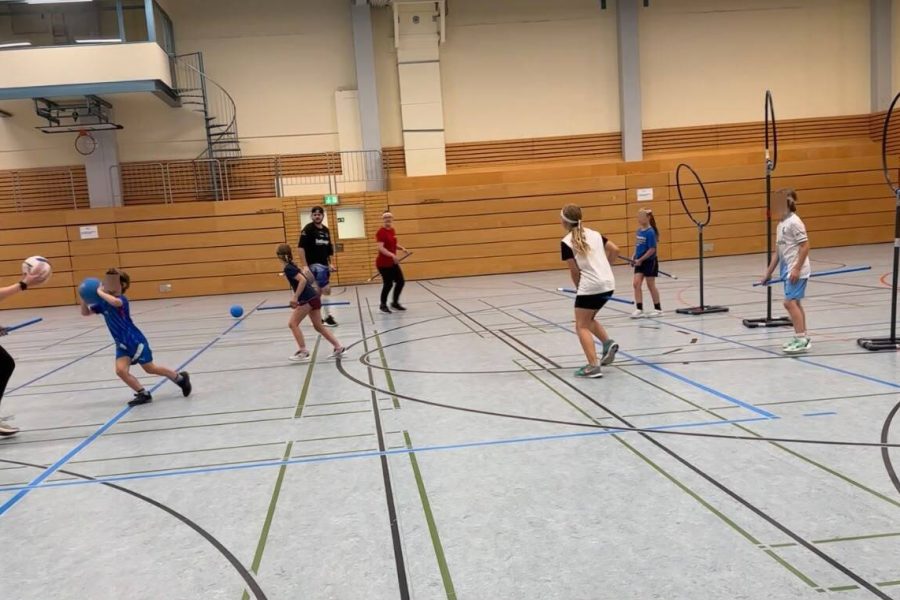 Kidditch Kinder und Erwachsene spielen gemeinsam Kidditch in einer Turnhalle